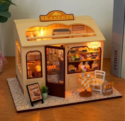 Miniature DIY bakery house kit with warm lighting, tiny pastries, shelves and cozy bakery decor
