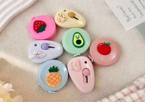 Cute mini cutter with pastel kawaii design held in hand beside a white keyboard