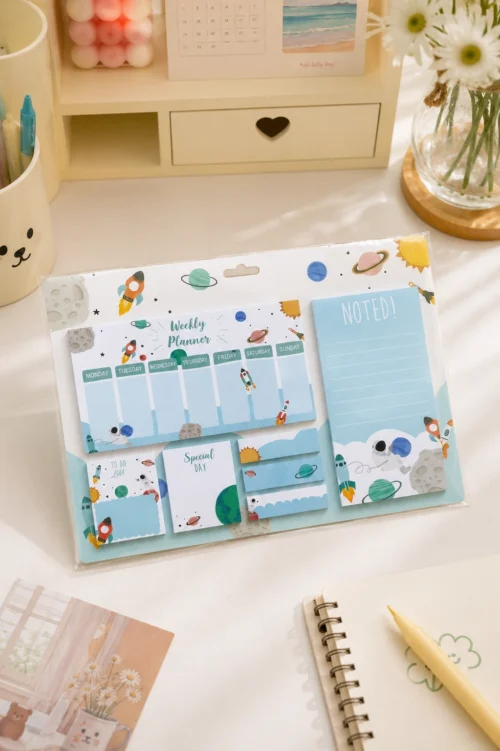 Space Weekly Planner Sticky Notes Set with rockets, planets, weekly planner, memo pads, sticky notes, page markers, and to-do list on a wooden desk.