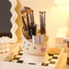 Cute desk organizer with pink bow and star cutouts holding pens and makeup brushes Cute desk organizer with pink bow and star cutouts holding pens and makeup brushes